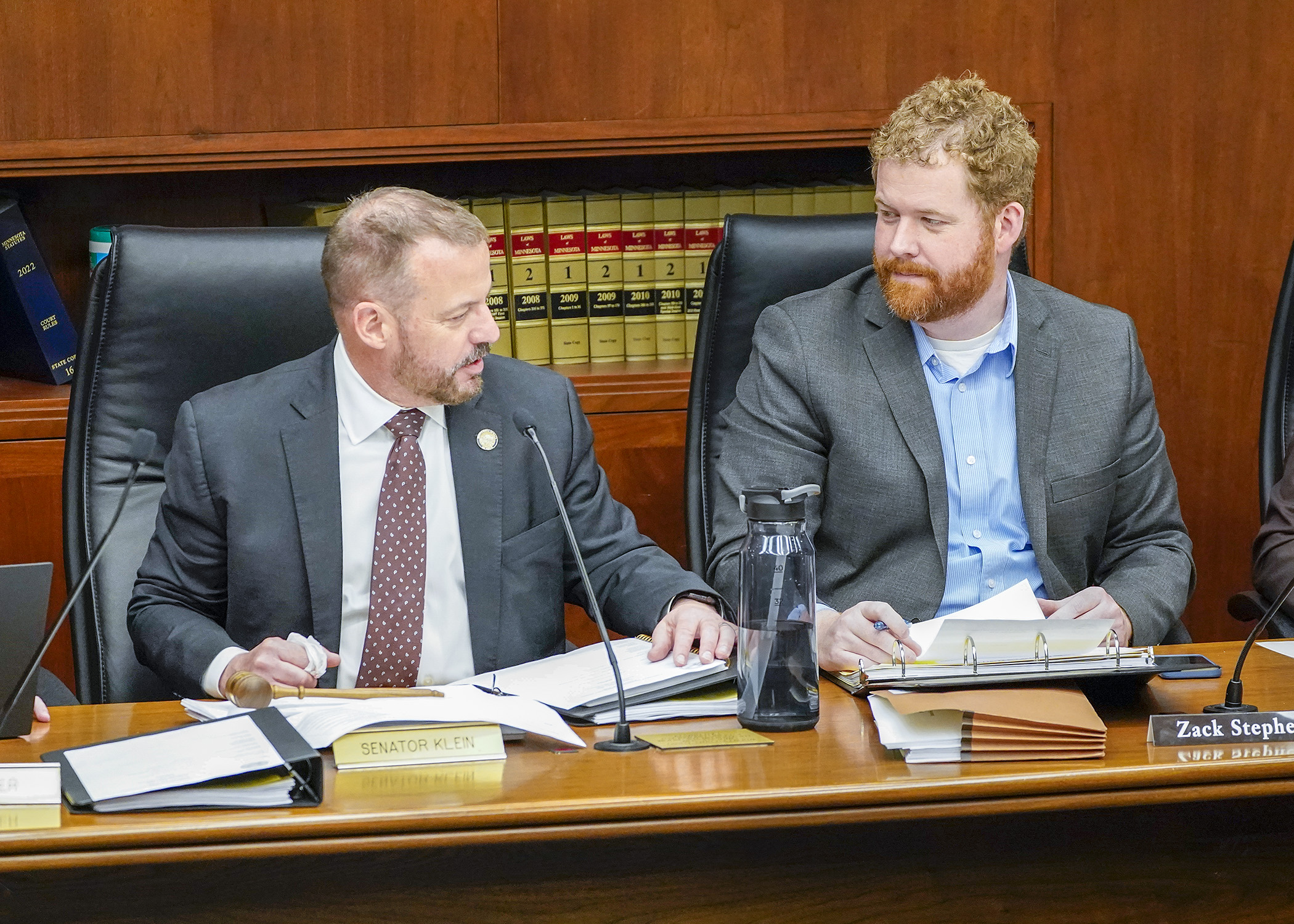 Sen. Matt Klein and Rep. Zack Stephenson confer before the first meeting of the omnibus commerce conference committee, May 3. (Photo by Andrew VonBank)